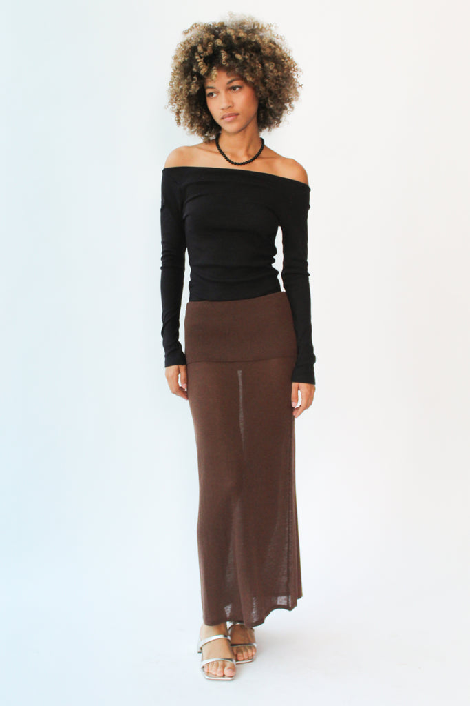 Woman wearing a black off-shoulder top and brown skirt on a white background