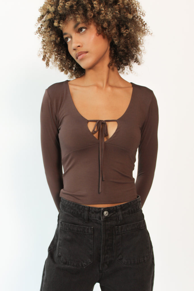 Woman wearing a brown long-sleeve top with a heart cutout design on a white background