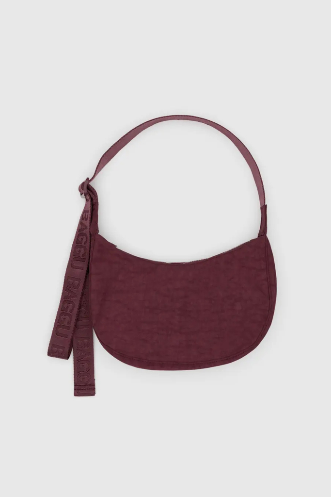 Maroon handbag with a strap on a light gray background