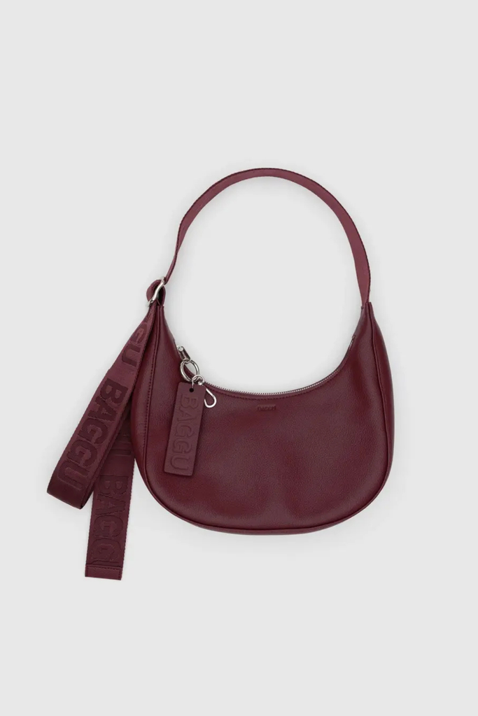 Maroon handbag with strap on a light gray background