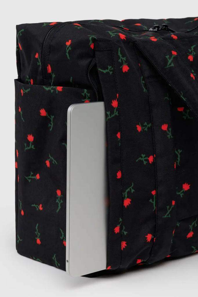 Black fabric with red floral pattern and a silver laptop on a white background