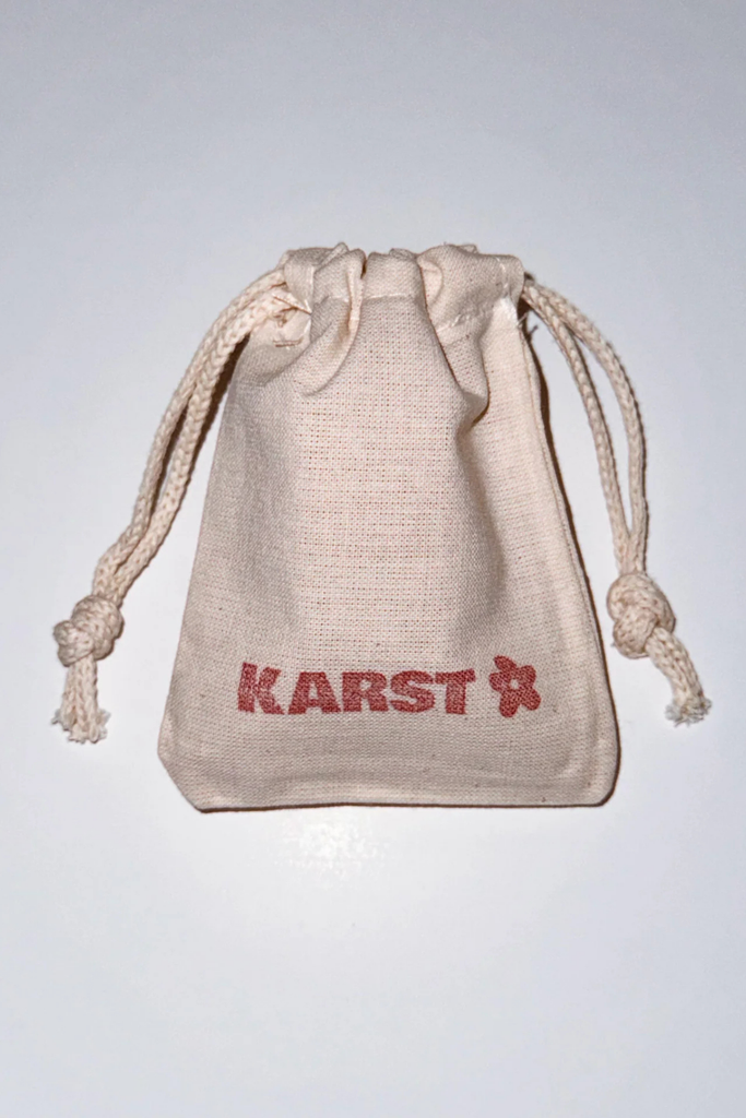 Beige drawstring bag with 'KARST' branding on a light gray background