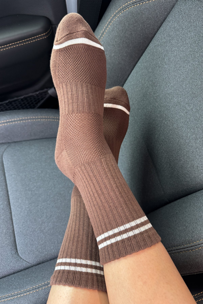 Brown socks with white stripes worn inside a car.