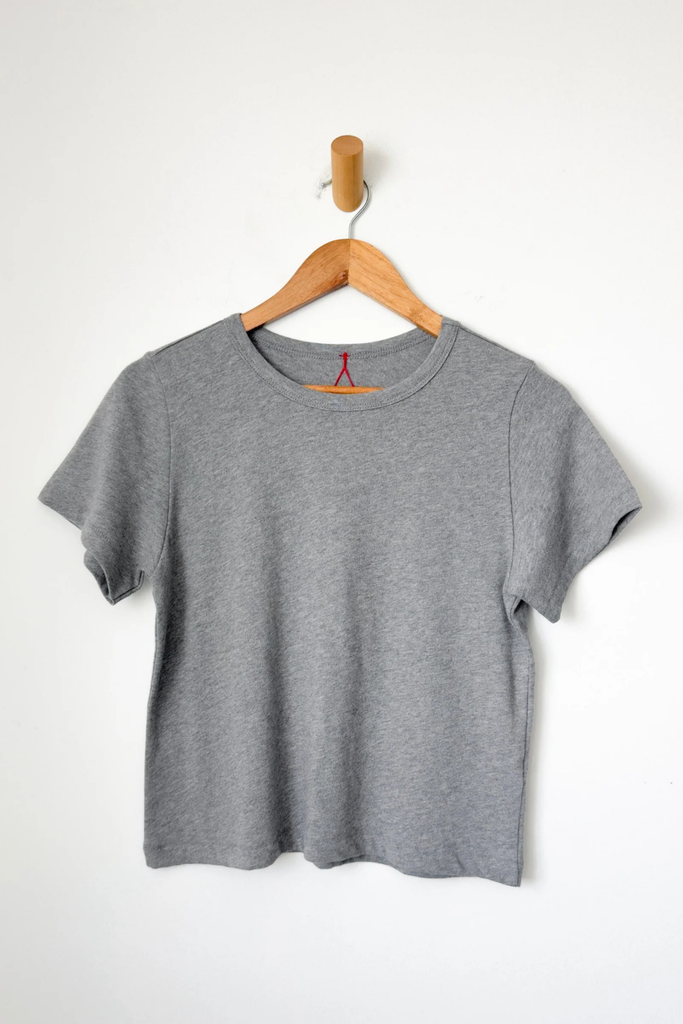 Gray t-shirt on a wooden hanger against a white background