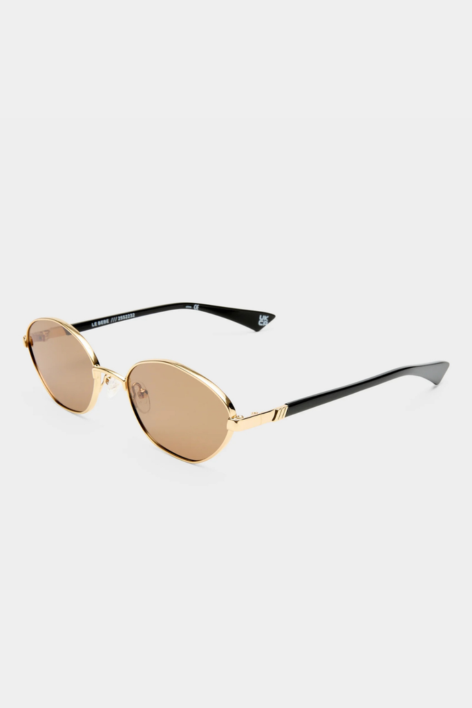 Gold sunglasses with black frames on a light gray background